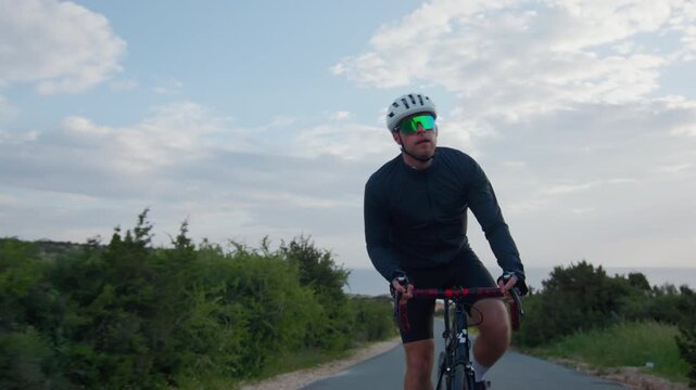 Athletic man cycling outdoors. Guy riding a bike training in a beautiful landscape.