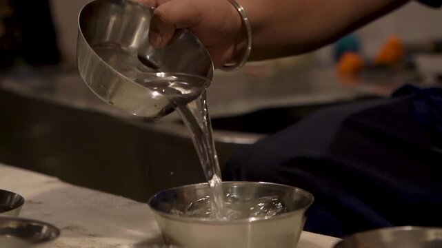 Hands cleaning kitchen utensils as part of community seva at Sri Harmandir Sahib.
