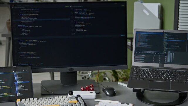 No people medium closeup of computer, laptop, tablet on desk of software engineer in big tech corporate office, script executed on screen with running code, representing mobile app development process