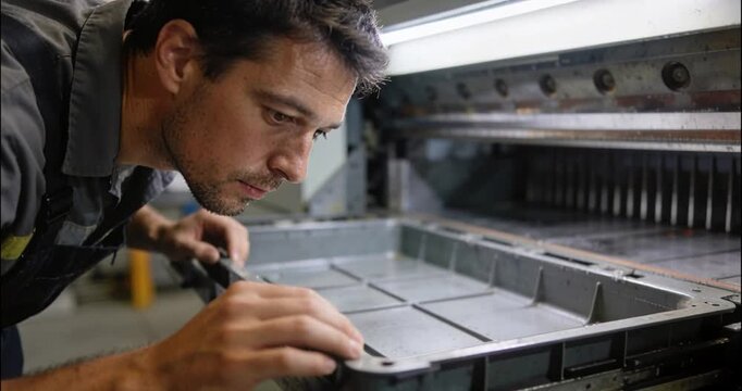 Man inspecting industrial printing equipment in a workshop setting