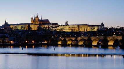 Obraz premium Evening lights illuminate Pragues majestic castle and Charles Bridge along the Vltava River