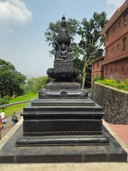 Obraz premium Traditional black stone Buddhist stupa (chaitya) standing in a historic heritage complex in Kathmandu, Nepal. The monument features intricate stone carvings and classic Nepalese architecture