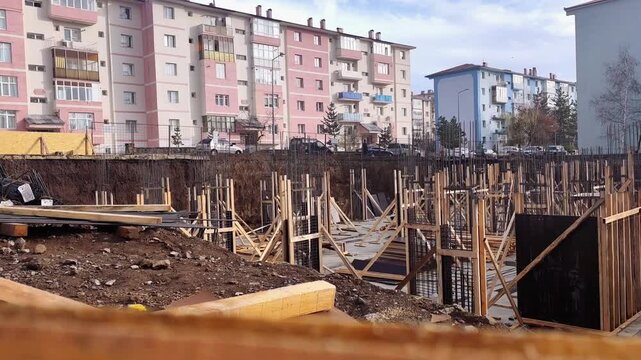 Static high-angle shot of a deep construction excavation pit with installed steel reinforcement rebar mesh for the building foundation.
