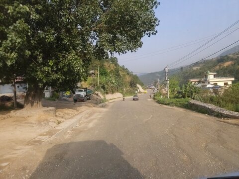Scenic mountain highway passing through hilly terrain with vehicles traveling along a dusty road construction section.