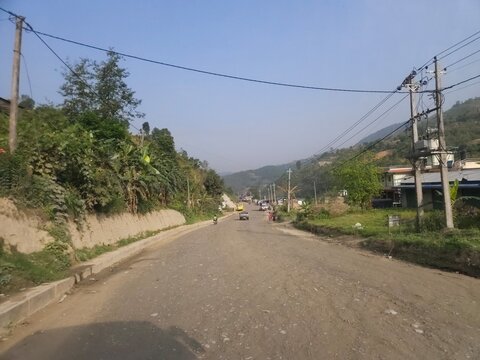 Scenic mountain highway passing through hilly terrain with vehicles traveling along a dusty road construction section.