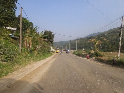 Scenic mountain highway passing through hilly terrain with vehicles traveling along a dusty road construction section.