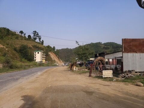Scenic mountain highway passing through hilly terrain with vehicles traveling along a dusty road construction section.