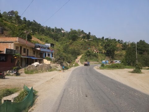 Scenic mountain highway passing through hilly terrain with vehicles traveling along a dusty road construction section.