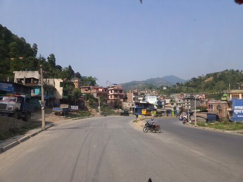 Scenic mountain highway passing through hilly terrain with vehicles traveling along a dusty road construction section.
