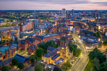 Obraz premium Leeds Minster in Leeds, West Yorkshire, England at dusk, aerial view over the historic church and surrounding Leeds skyline with illuminated city buildings.