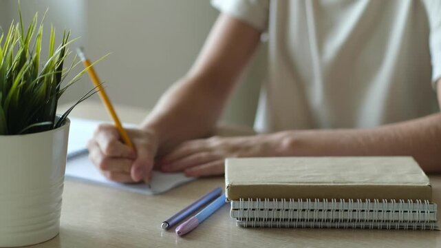 Child girl doing homework. Student writing, studying at home. Focus on books. Education and school tasks concept
