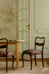 Fototapeta premium Elegant dining room interior with a light wooden table and two ornate chairs, showcasing classic design and warm ambiance