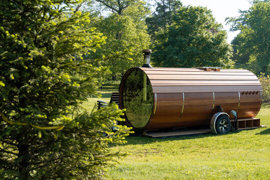 Mobile wooden sauna on wheels in a forest next to a pine tree, horizontal composition highlighting outdoor wellness, nature retreat, and sustainable lifestyle