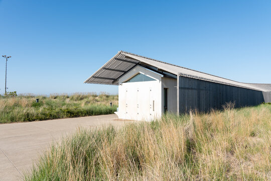Coastal shower facility with wooden slatted roof, blending into a seaside environment horizontal photo