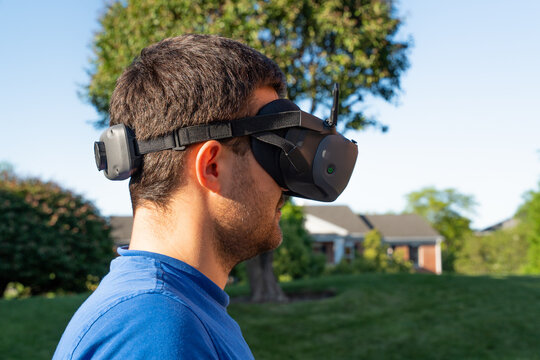 Horizontal side view of a man wearing FPV goggles for drone control, highlighting immersive first-person flight experience, modern aerial technology, and advanced drone piloting setup