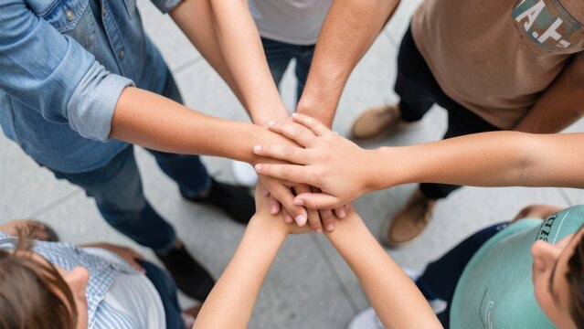 Close up top view of young people putting their hands together. Friends with stack of hands showing unity and teamwork.