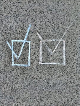 Two hand-drawn chalk checkmark symbols in boxes on grey granite tile, concept of success, checklist and task completion