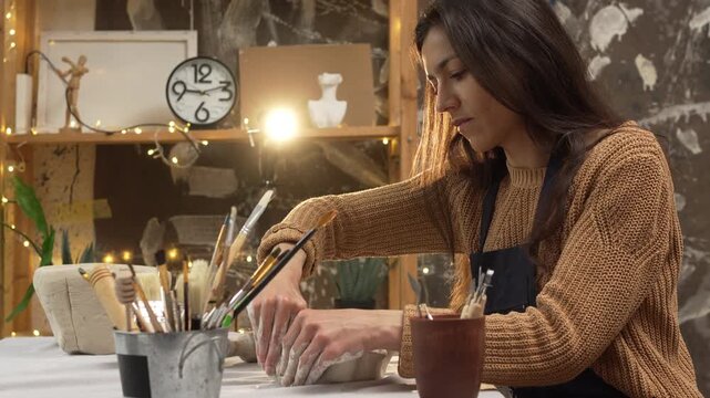 Latin woman creating handmade clay pottery in ceramic workshop during leisure time. creativity, artisan hobby, sculpture, craft and artistic lifestyle