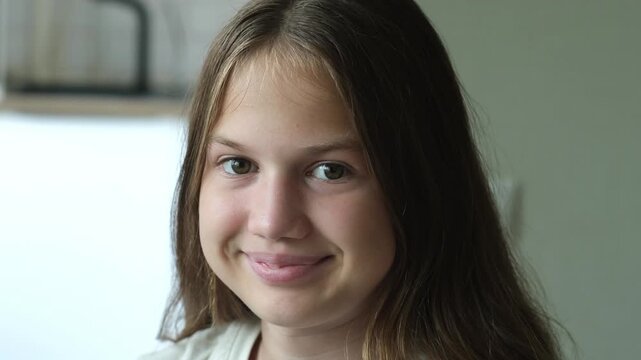 Portrait of smiling kid girl at home looking at camera close up