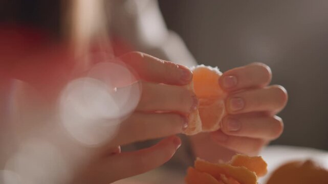 Warm scene with hands and orange slices. Closeup of hands gently splitting orange pieces in intimate setting. Moments of sharing citrus as warm candlelight bathes cozy kitchen atmosphere