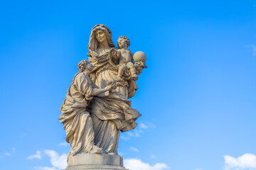 Fototapeta premium Historic baroque statue of Saint Anne holding baby Jesus and young Mary on Charles Bridge in Prague, Czech Republic.