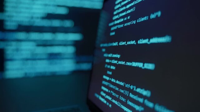 Close up of laptop screen with programming code in dark environment, blue glowing code lines on display and background. Data science software development and coding concept. 