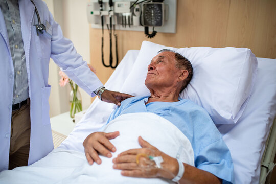 Doctor comforting elderly patient bedside.