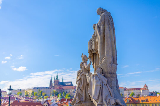 Historic stone statue of Saints Cyril and Methodius on Charles Bridge with Prague Castle in the background, Czech Republic.