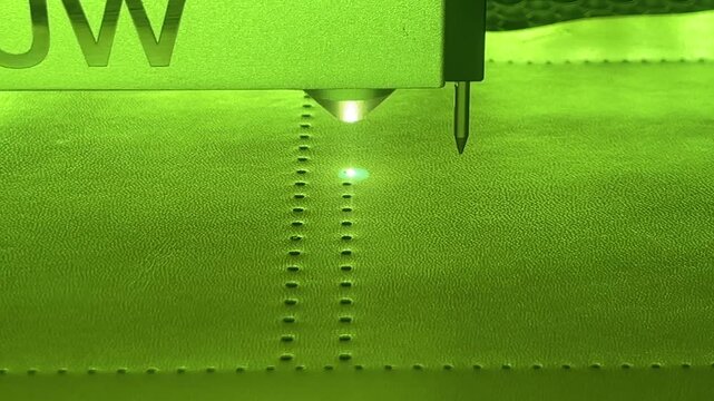 CNC laser cutter engraving pattern on green leather close-up