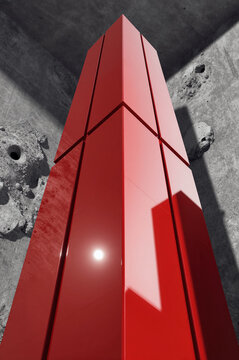 Column composed of segmented red panels rises vertically within a concrete structure under harsh sunlight that casts sharp geometric shadows along its glossy surface.