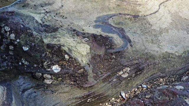 Close up view of patterned rock formations and small tide pools on the coastal shore