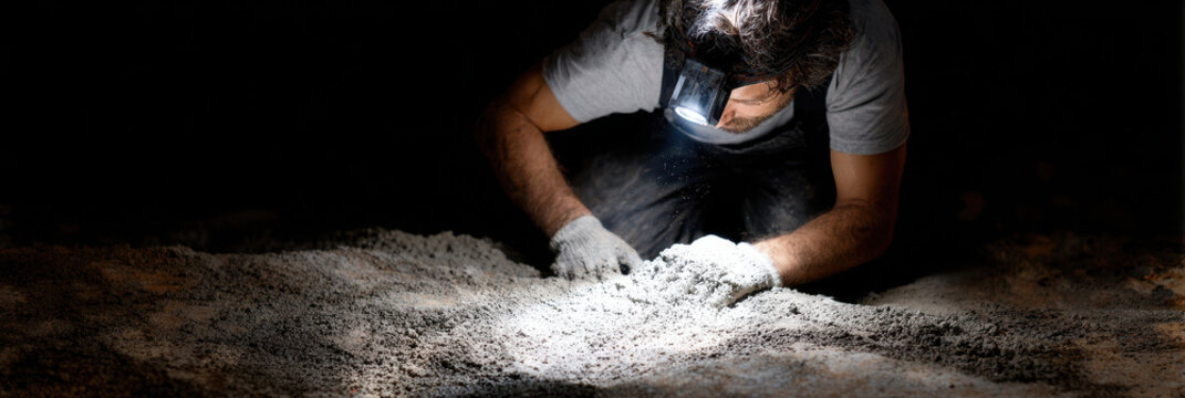 Night shift construction worker illuminating fr b abb Night shift construction worker wearing headlamp, focused ground, searching or inspecting soil dark environment, illuminated by bright light