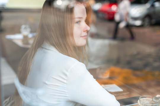 Woman gazing through cafe window.