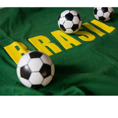 Obraz premium Brazil Football Concept with Small Soccer Balls on Green and Yellow Brasil Jersey Fabric