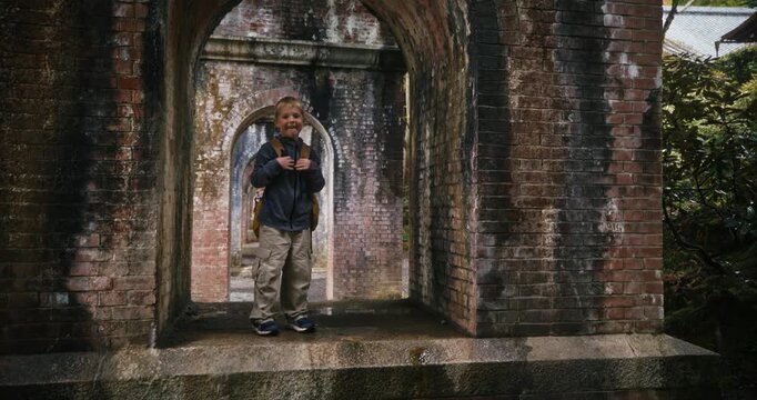 Young boy standing in brick arch and smiling - slow motion, steady cam