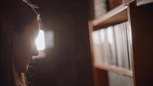 Profile silhouette reaching book on shelf in backlit room, warm beam highlights wooden spines, slow deliberate motion evokes quiet study and discovery, cozy archival mood with soft dust particles