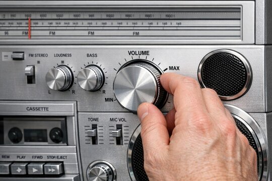 A person's hand adjusting the volume control on a radio