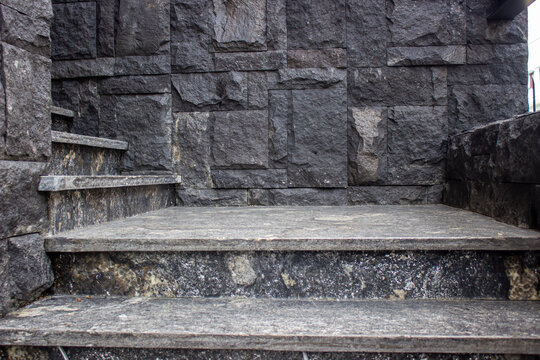 Building entrance staircase with dark grey granite marble steps perfectly matching the textured black andesite natural stone cladding wall.