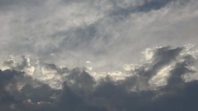 Dramatic view of dark grey storm clouds gathering and moving over a bright blue afternoon sky. High contrast footage illustrating a changing climate and approaching rain.