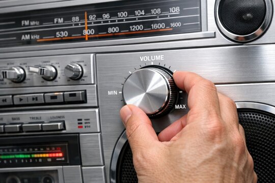 A person fine-tuning the volume on an old-fashioned radio