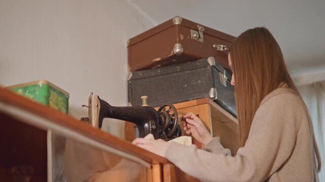 Woman using antique sewing machine. Quiet woman focuses on restoring linen with classic sewing tools. Calm woman skillfully repairs linen curtain using old sewing machine in cozy setting