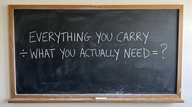 A thought-provoking mathematical formula handwritten in chalk on a blackboard, symbolizing the process of dividing life's excess baggage by true essentials to find ultimate simplicity