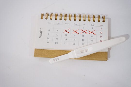 pregnancy test showing two stripes on white clean calendar . Calculation of ovulation day. Planning maternity. Gynecology and women's health concept. Top view
