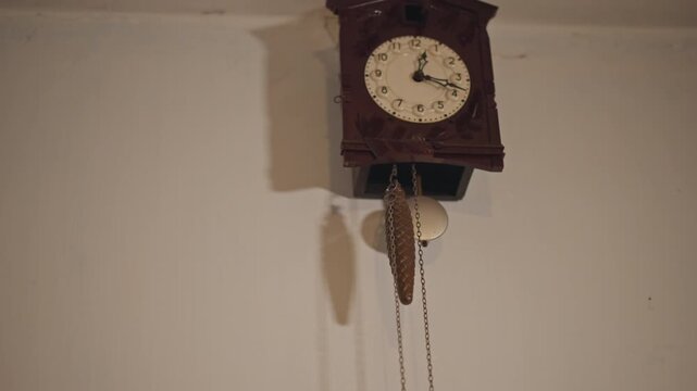 Vintage clock details. Closeup of antique clock with gentle swinging. Cassette clock with wood grain and muted glow. Detailed view of vintage cuckoo clock showing chains and soft ticking sound
