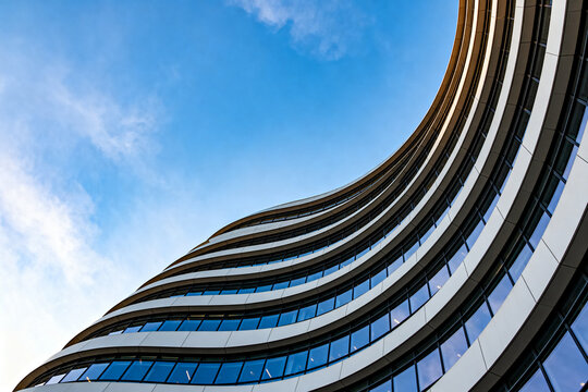 Modern Curved Office Building with Glass Windows Against Clear Blue Sky