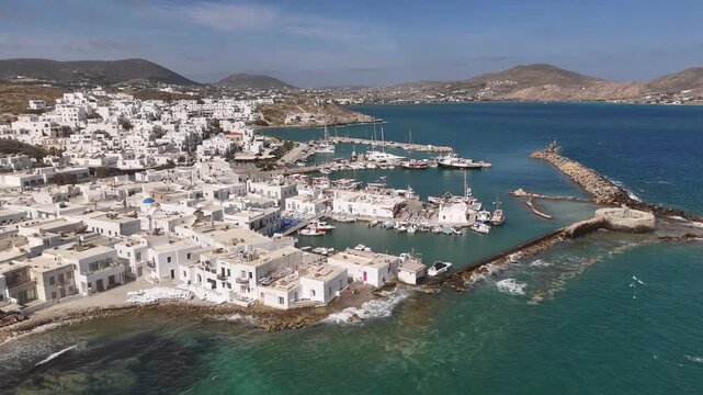 4K drone pan of Naoussa harbor with waves crashing against ancient Venetian castle, Paros, Greece