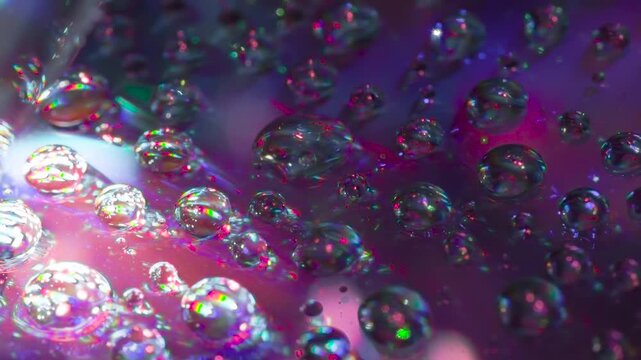 Surface is Covered with Sparkling Drops. A multitude of round droplets of a chemical reagent on a dark mirror surface slowly swirl in a cloud of laser beams