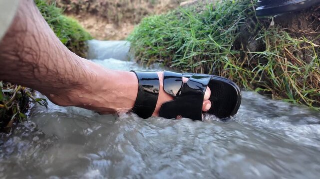 black leather sandals resembling starlet shoes, worn outdoors in nature by the water.