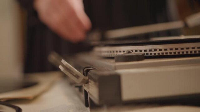Closeup white hands calibrating tonearm on vintage turntable, warm lamp glow, careful technician adjusting needle and cartridge, visible platter edge and label, tabletop tools and paper, shallow depth