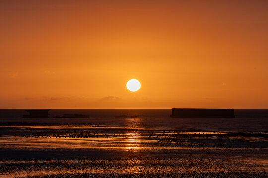 Golden sunset over the WWII artificial Mulberry harbor in Arromanches-les-Bains